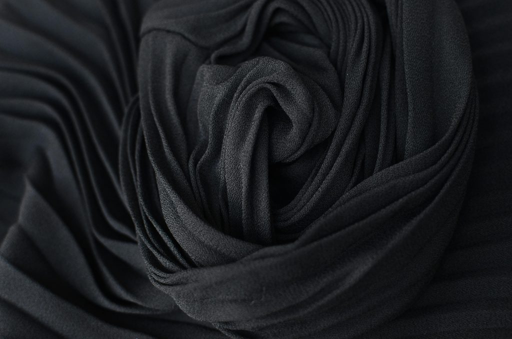 Top view abstract textured background of dark gray pleated textile placed on table